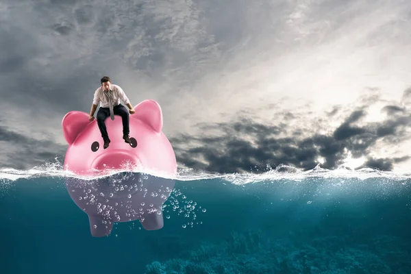 Business man in financial trouble sails on piggy bank in bad waters due to the crisis — Stock Photo, Image