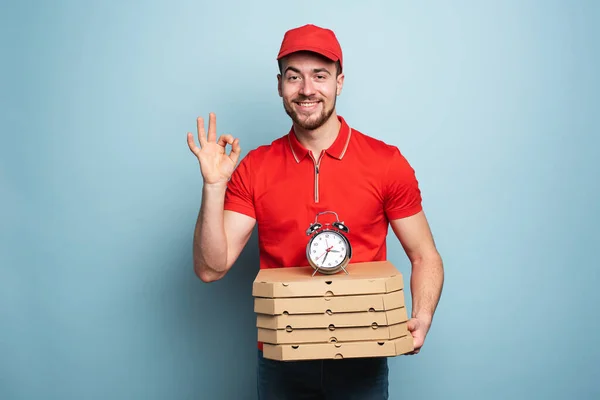 Courier is punctual to deliver quickly pizzas. Cyan background. — Zdjęcie stockowe