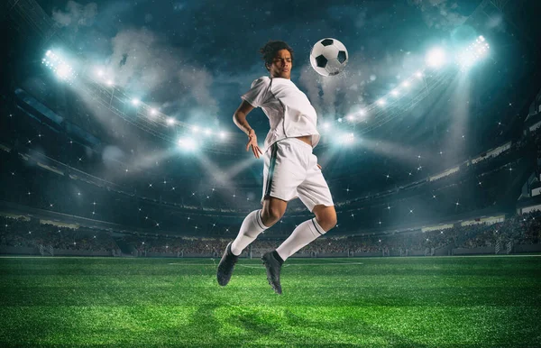Футболист останавливает мяч акробатическим прыжком на стадионе во время ночного матча — стоковое фото
