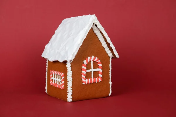 La casa de pan de jengibre comestible hecho a mano y la decoración de la nieve sobre fondo rojo — Foto de Stock