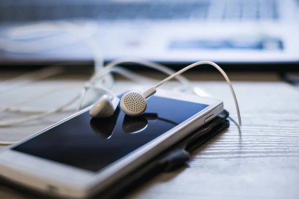 Office desk with mobile phone and headphones. — Stock Photo, Image