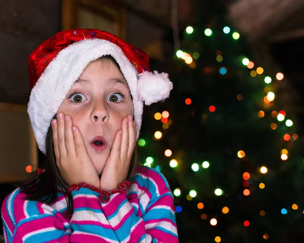 Gelukkig kind meisje in een kerstmuts wachten op een wonder. — Stockfoto