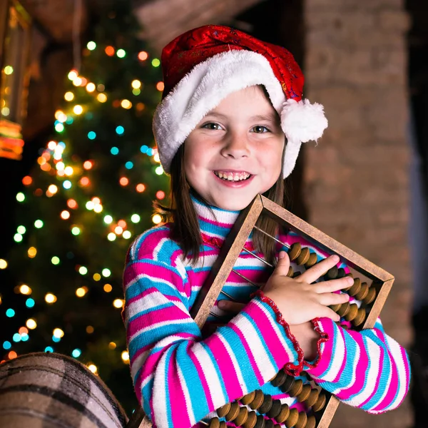 Happy child girl in a Christmas hat waiting for a miracle. — Stock Photo, Image