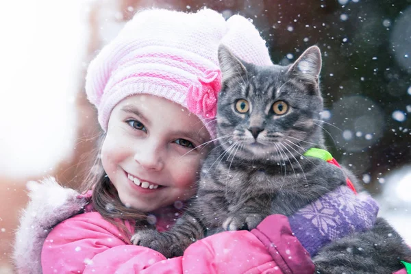Bambino abbraccia un gatto in strada in inverno . — Foto Stock