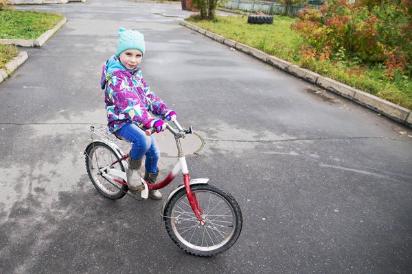 Niña montando en bicicleta en el parque de otoño —  Fotos de Stock