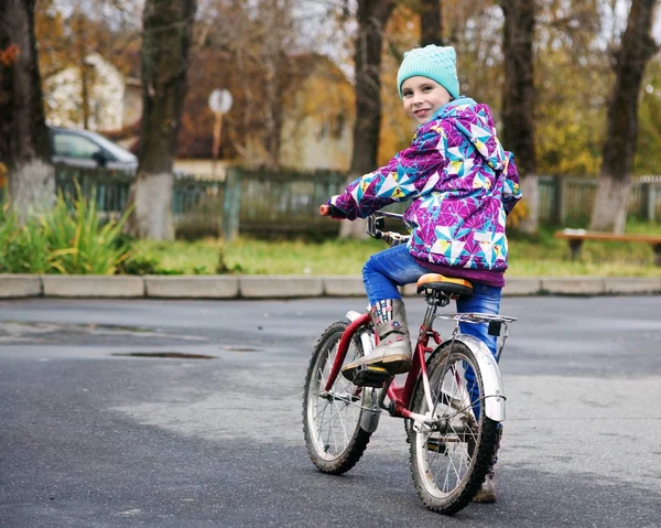 Маленькая девочка на велосипеде в осеннем парке — стоковое фото