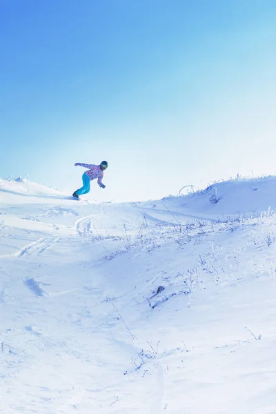 Jeden snowboardzista jeździć z wysokiej snowy góry pod błękitne niebo. — Zdjęcie stockowe