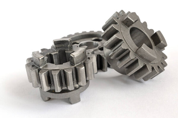 Три металлические шестерни на белом фоне
