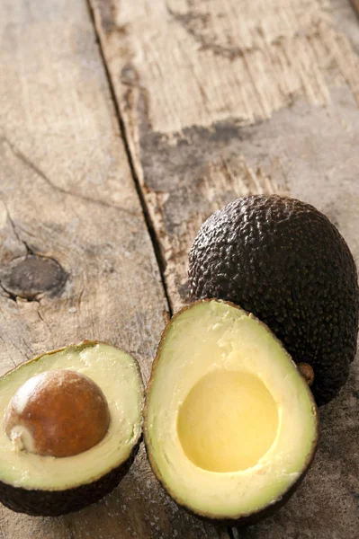 Ripe halved avocado pear on a rustic table — Stock Photo, Image