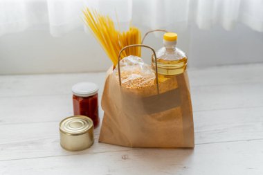Mal bağışları için kağıt torba, komşular için karantina yardım konsepti. Ayçiçeği yağı, makarna, bezelye, konserve yiyecek, domates ezmesi.