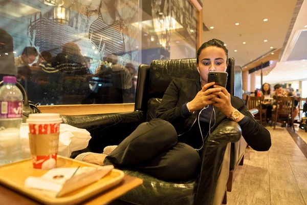 Девушка сидит в кресле в кофейне Starbucks — стоковое фото