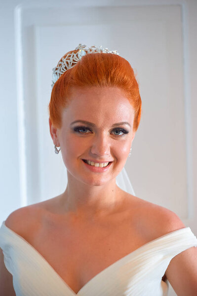 Indoor portrait of young beautiful red-haired bride