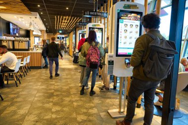 BERLIN, GERMANY - CIRCA SEPTEMBER, 2019: people use self ordering kiosks at McDonald's restaurant in Berlin.