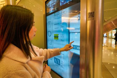 Hong Kong, Çin - 23 Ocak 2019: Kadın Hong Kong 'daki New Town Plaza alışveriş merkezinde interaktif dokunmatik ekran kullanıyor