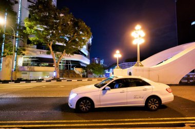 SINGAPORE - CIRCA APRIL, 2019: a white car seen on a road in Singapore at night.