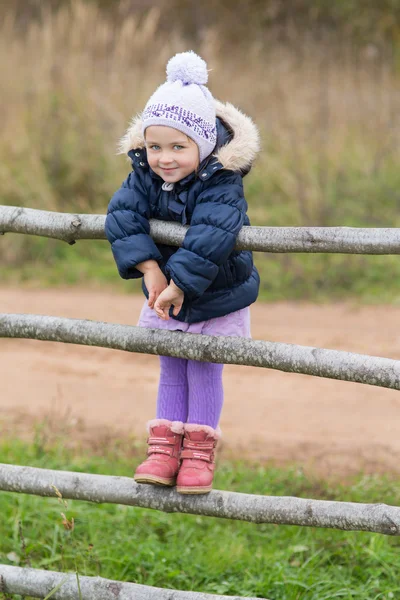 Meisje op een houten hek — Stockfoto