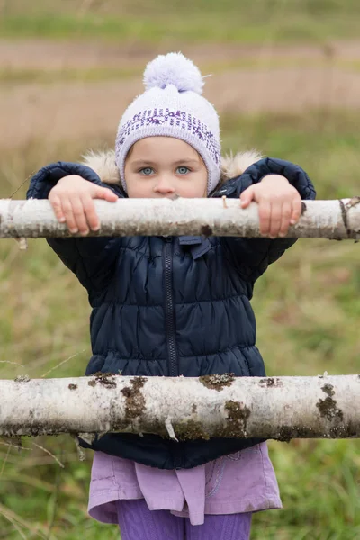 Little girl near a wooden fence — Stock Photo, Image