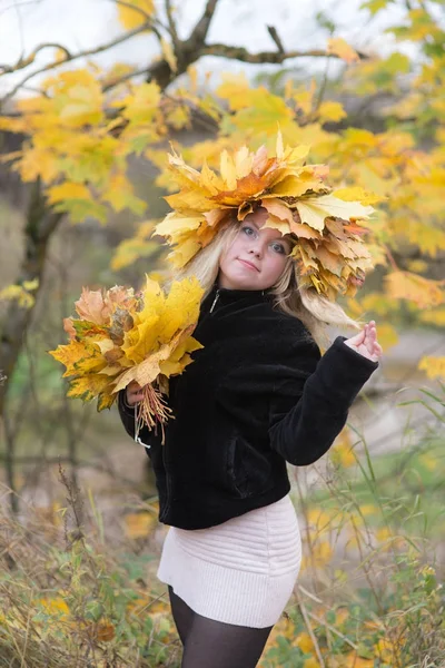 Niña en una corona de hojas de otoño — Foto de Stock