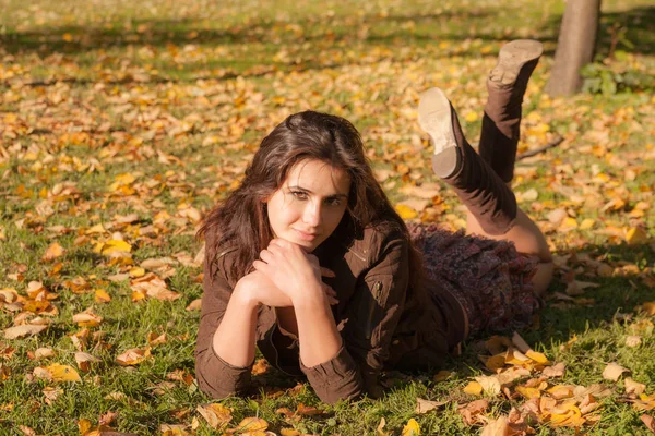 Flicka på gräs med höstlöv — Stockfoto