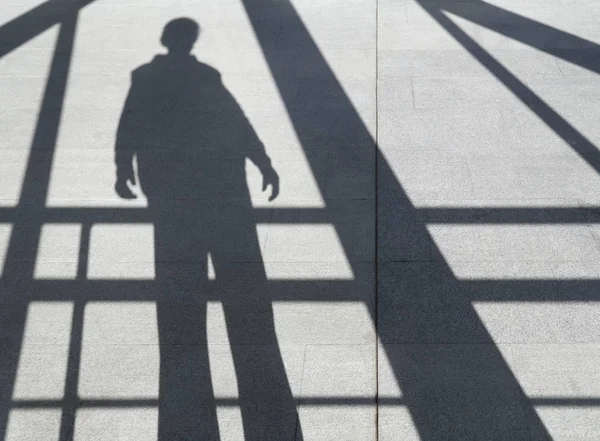 Sombra de un hombre en la acera entre las vigas — Foto de Stock