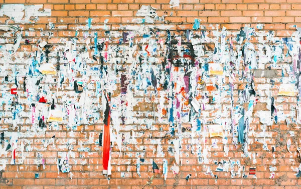 Muro de ladrillo con los restos de anuncios antiguos y carteles — Foto de Stock