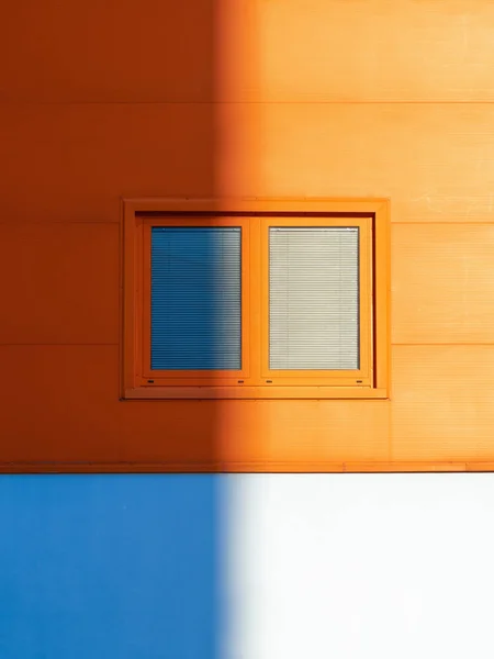 Окно с жалюзи и оранжевая стена наполовину в тени . — стоковое фото