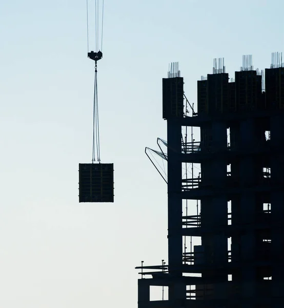 O guindaste levanta algo sobre a casa em construção . — Fotografia de Stock