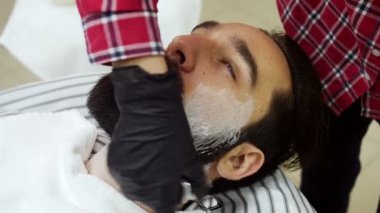 Yüz tıraş köpüğü bir bez tarafından uygulanan Kuaför