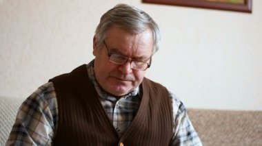 Yaşlı adam evde gazete okuma.