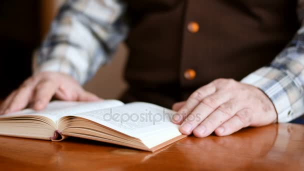 Oude man zit op de Bank thuis lezen van een boek — Stockvideo
