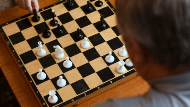 Ребенок играет с бабушкой и дедушкой в шахматном доме — стоковое видео