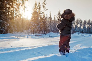 Çocuk arka plan üzerinde güneşli orman ile kış karlı yolda yürürken. Urallar manzara 