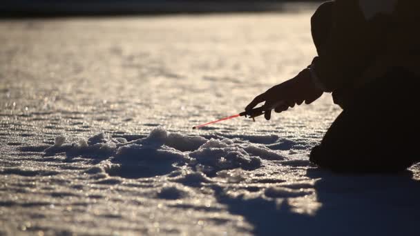 渔夫在冰封的湖面上 在晴朗的天空下钓鱼 — 图库视频影像