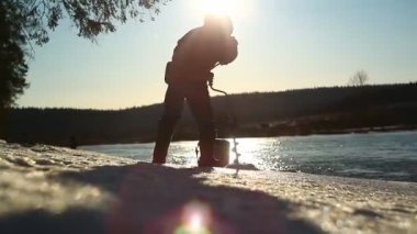 Balıkçı, ilkbaharda nehirde buz kazar. Donmuş gölde açık havada balık tutan Fishman. Kışın balık. Güneşli kış gününde nehirde bir balıkçı. 