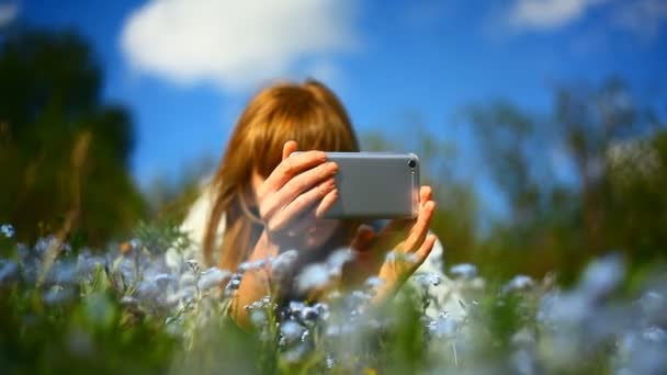 Egy fiatal lány virágokat fényképez egy okostelefonon.