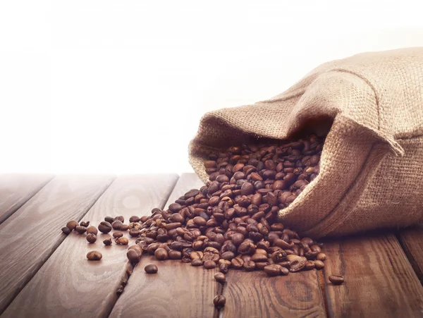 Roasted coffee beans poured out of a sack — Stock Photo, Image