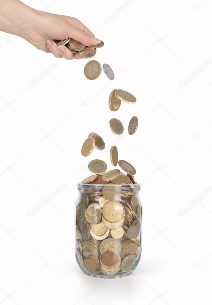 coins falling into the glass jar from womens hand isolated 
