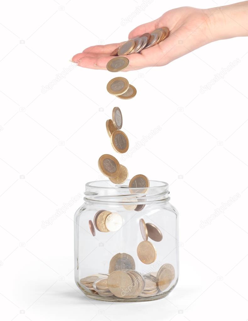 coins falling into the glass jar from hand isolated