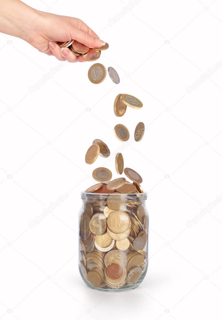 coins falling into the glass jar from womens hand isolated 