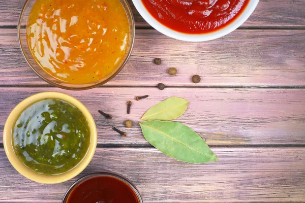 Bowls with sauces on a wooden background, top view — Stock Photo, Image