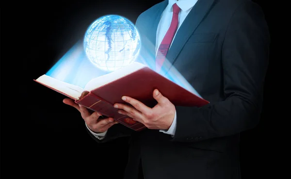Man in suit holding a opened book with planet hologram. Technolo — Stock Photo, Image