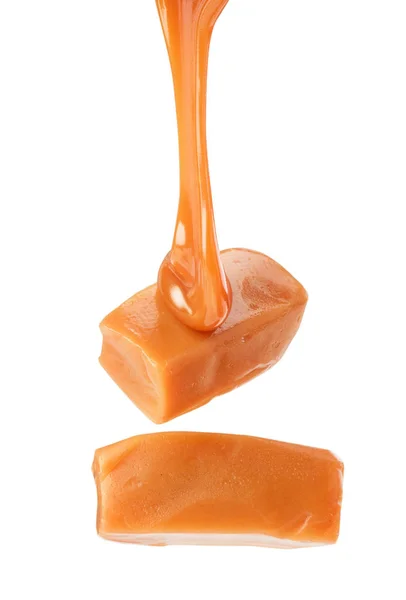 Líquido caramelo fluente com doces em um fundo branco — Fotografia de Stock
