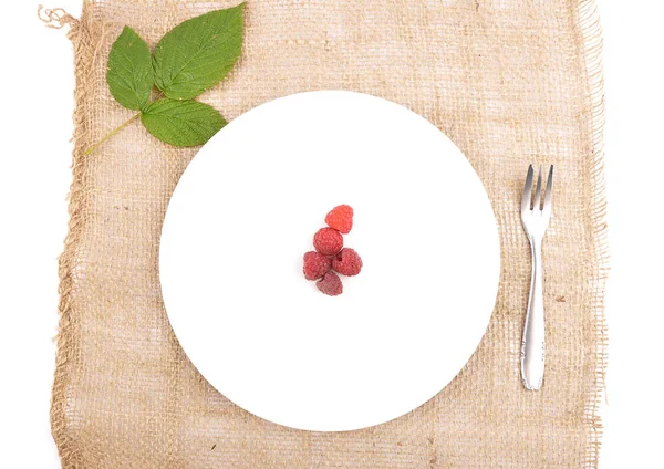 Framboesas vermelhas no prato e juta — Fotografia de Stock