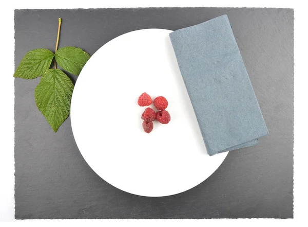 Красная малина на тарелке и сланце — стоковое фото