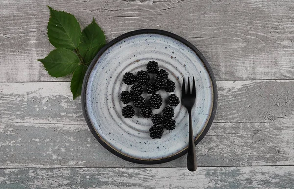 Blackberries on plate and weathered wood — Stock Photo, Image