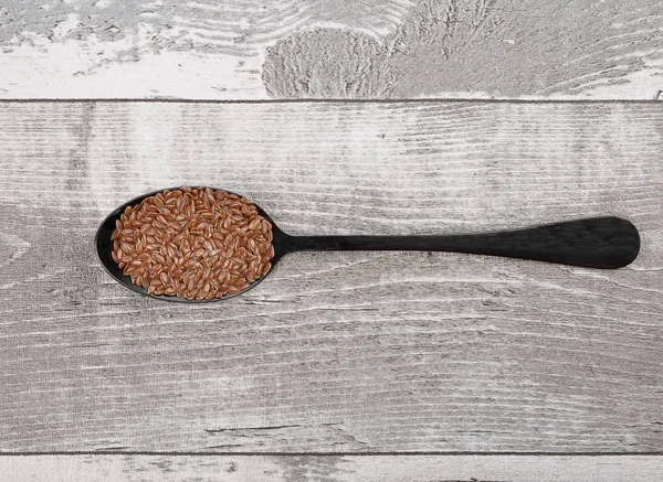 勺子和风化木头上的亚麻籽 — 图库照片