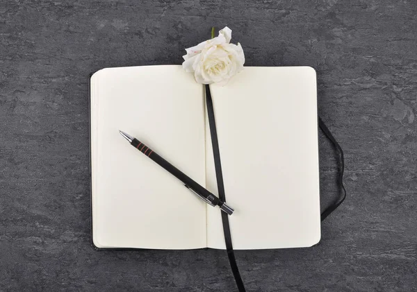 Σημειωματάριο, στυλό και το λευκό τριαντάφυλλο στην πλάκα — Φωτογραφία Αρχείου