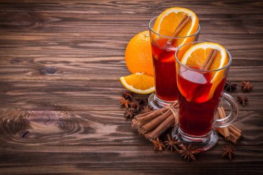 Cam mulled şarap, baharat ve ahşap arka plan üzerinde meyve ile
