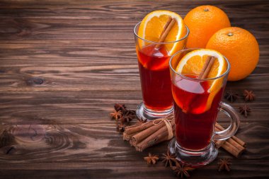 Cam mulled şarap, baharat ve ahşap arka plan üzerinde meyve ile