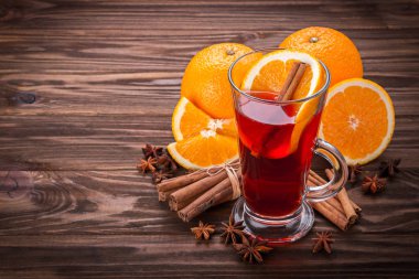Cam mulled şarap, baharat ve ahşap arka plan üzerinde meyve ile